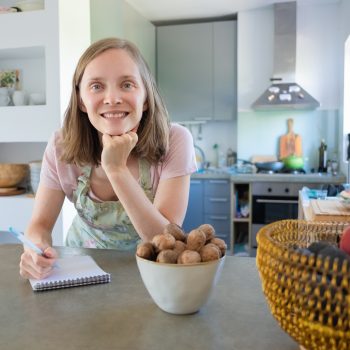 Happy woman leaning on counter with fruits