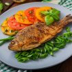 Fried fish carp and fresh vegetable salad on wooden background.