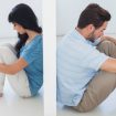 Sitting couple are separated by white wall and looking depressed